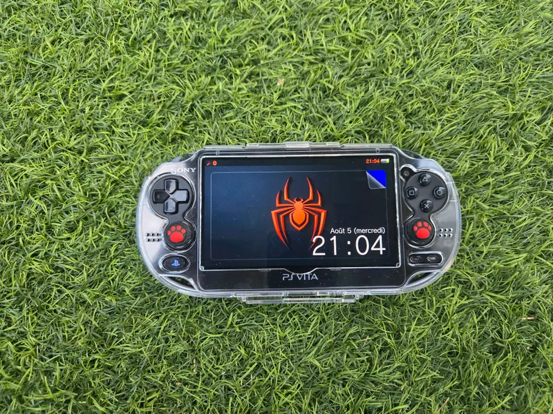 PS Vita 1000 noire en coque transparente, écran OLED allumé sur un thème Flower Boy