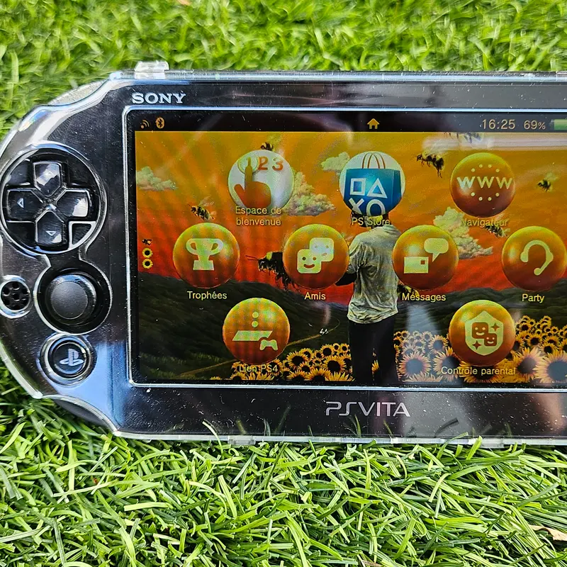 PS Vita 2000 noire en coque transparente, écran LCD allumé sur un thème Tournesols