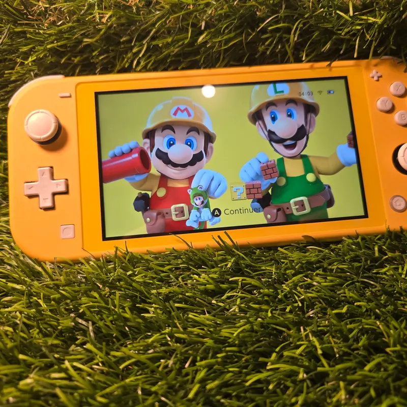 Nintendo Switch Lite jaune, écran allumé sur un thème Super Mario